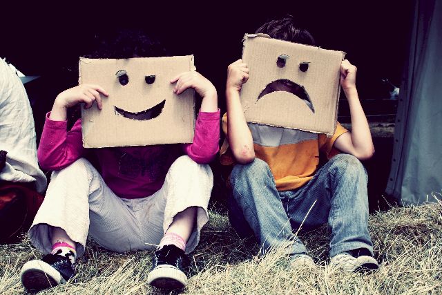 2 enfants, assis par terre, expriment leurs émotions avec des cartons, l’un est content et espiègle, l’autre est vraiment contrarié, voire en colère. C’est un moyen original pour partager leurs émotions avec leurs parents et signifier leur accord ou désaccord.