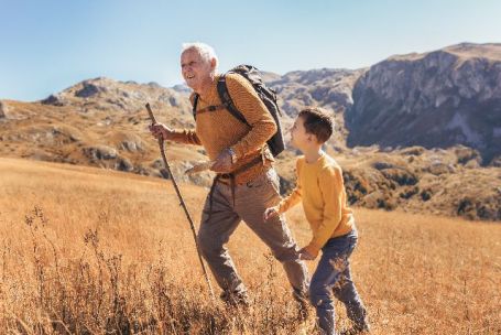 Un grand père fait une rando en montagne avec son petit-fils