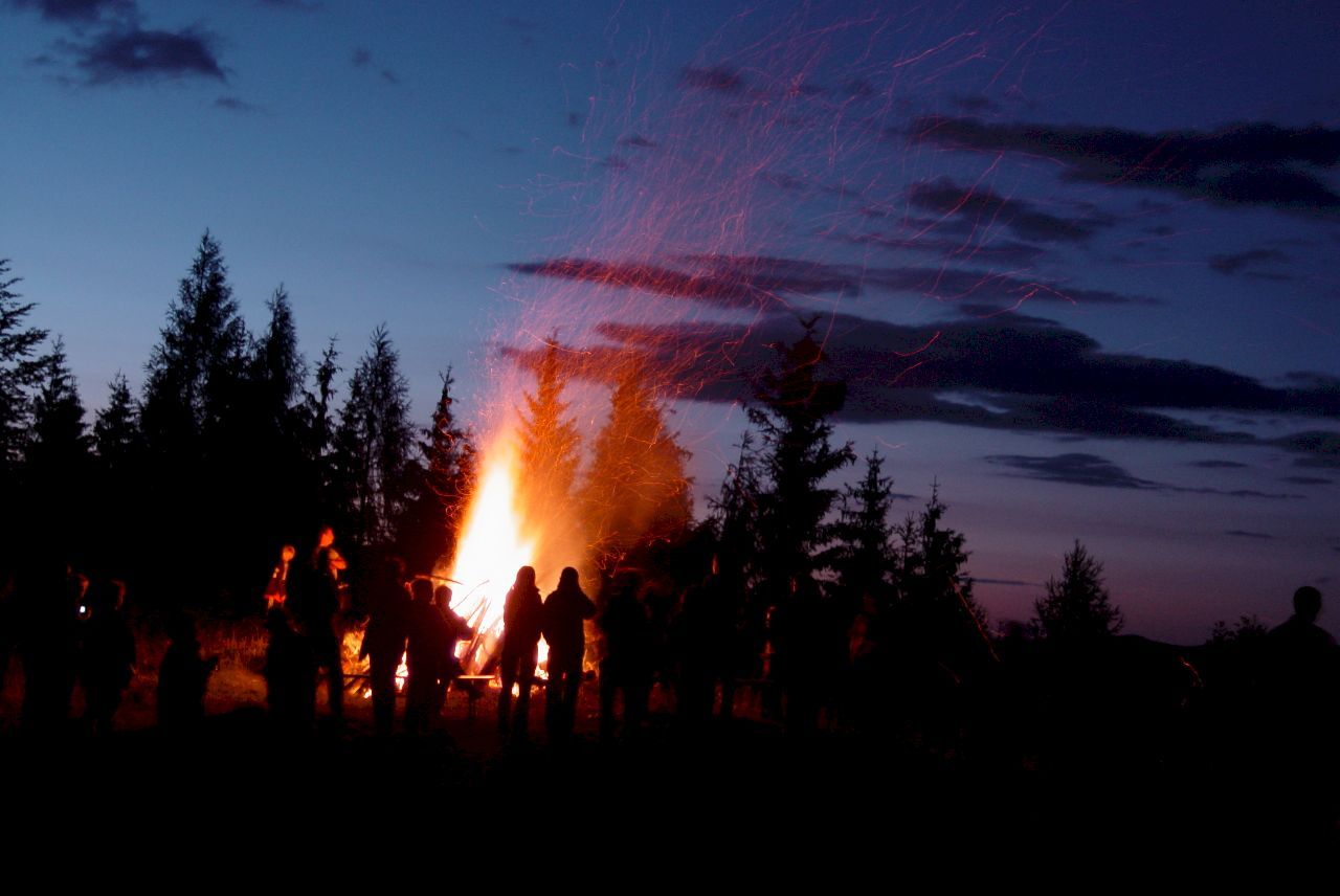 Famille et amis se retrouvent de nuit pour fêter le solstice d’été autour d’un grand feu.